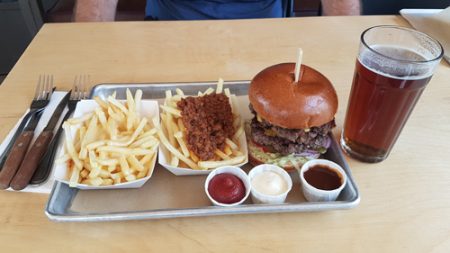 Fries with melted cheese, fries with minced meat, hamburger and a cold beer